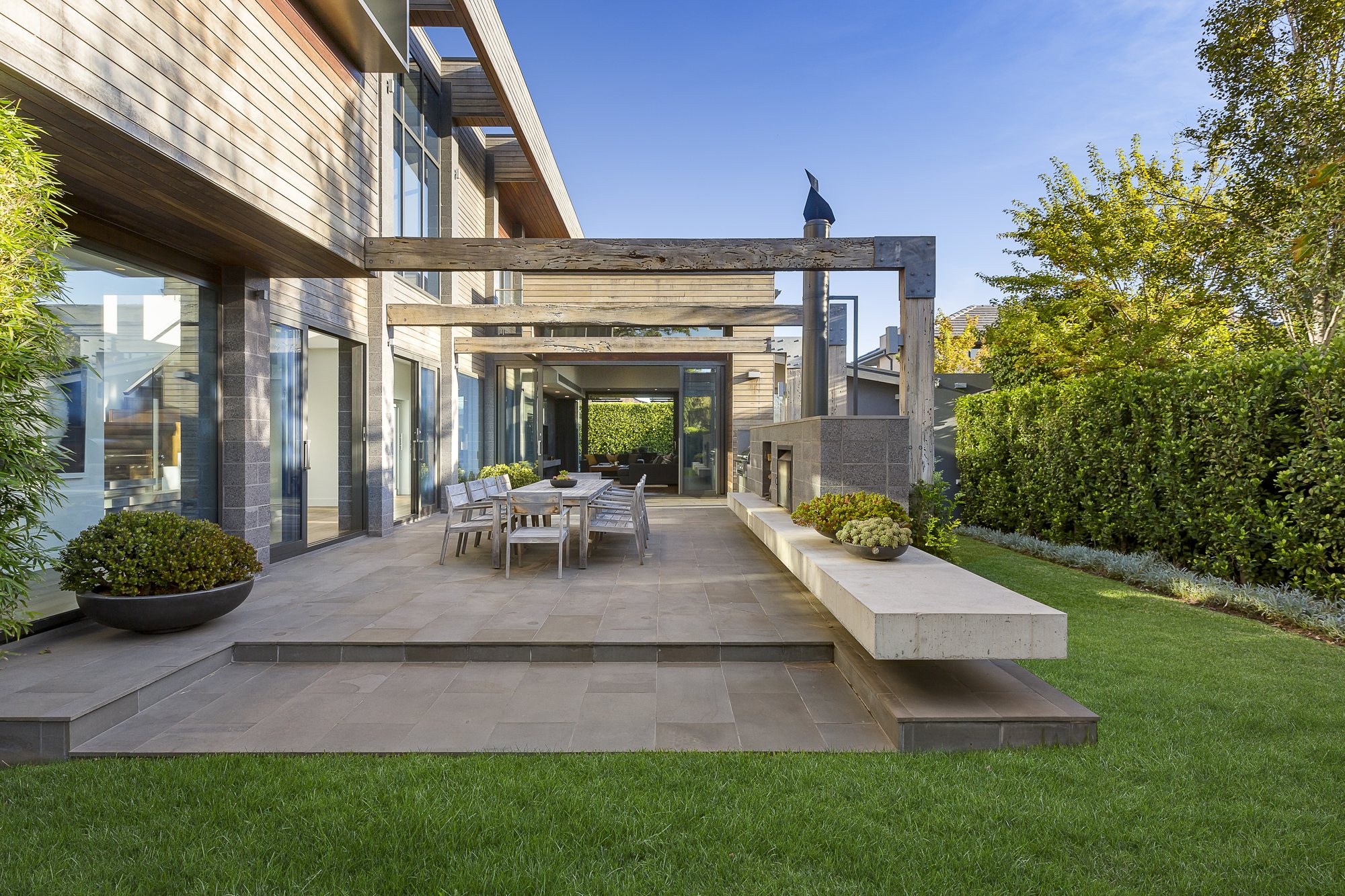 Terrasse eines Einfamilienhauses mit Pergola, Essbereich im Freien und privatem Rasen
