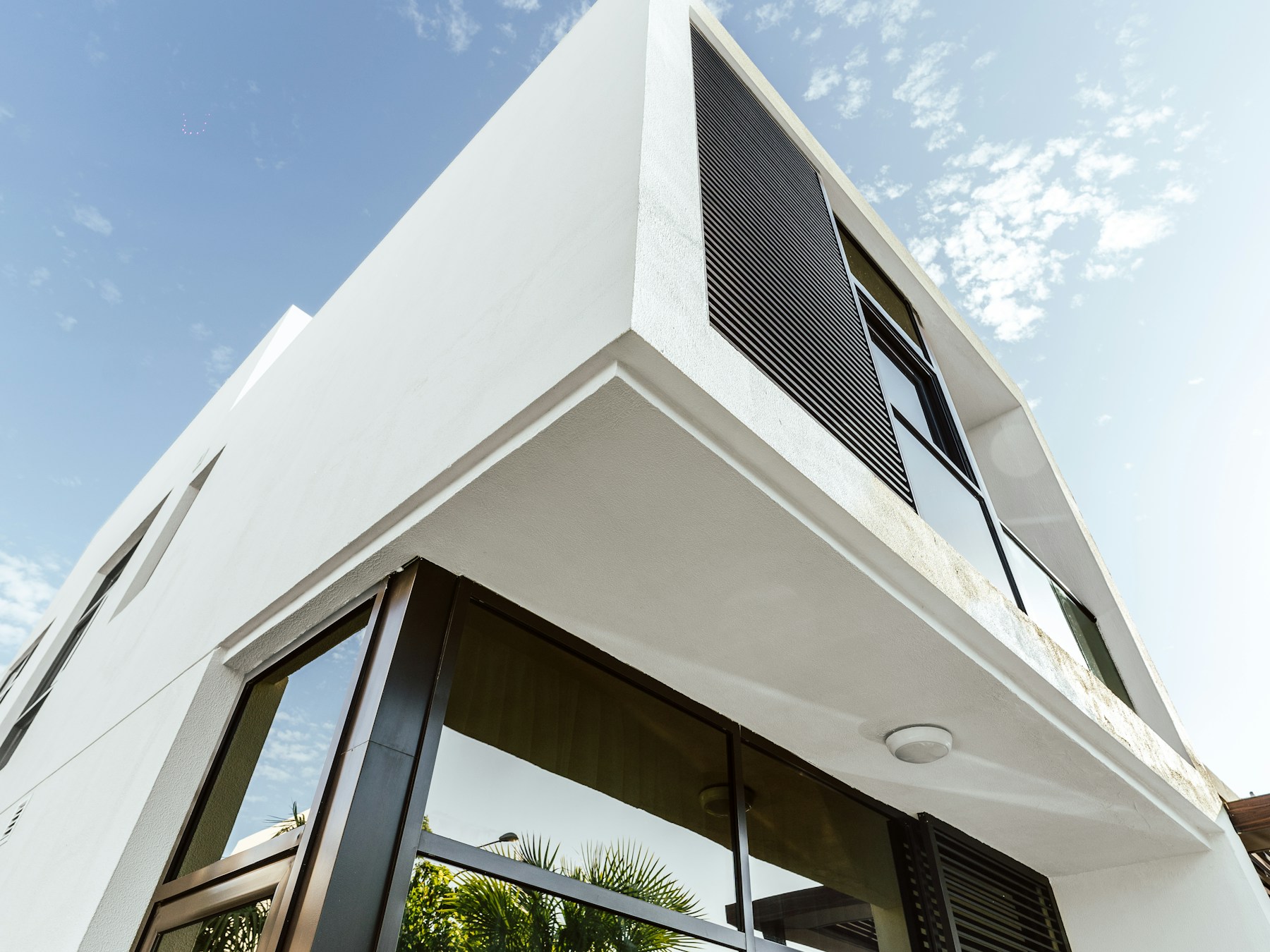 Angle d’une villa blanche contemporaine à Dubaï, avec des claustras en bois sombre, vue en contre-plongée